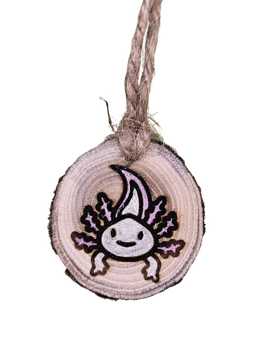 A wood burned Christmas tree ornament depicting an axolotl with a laser engraved hand drawn design, suspended by a twine string.