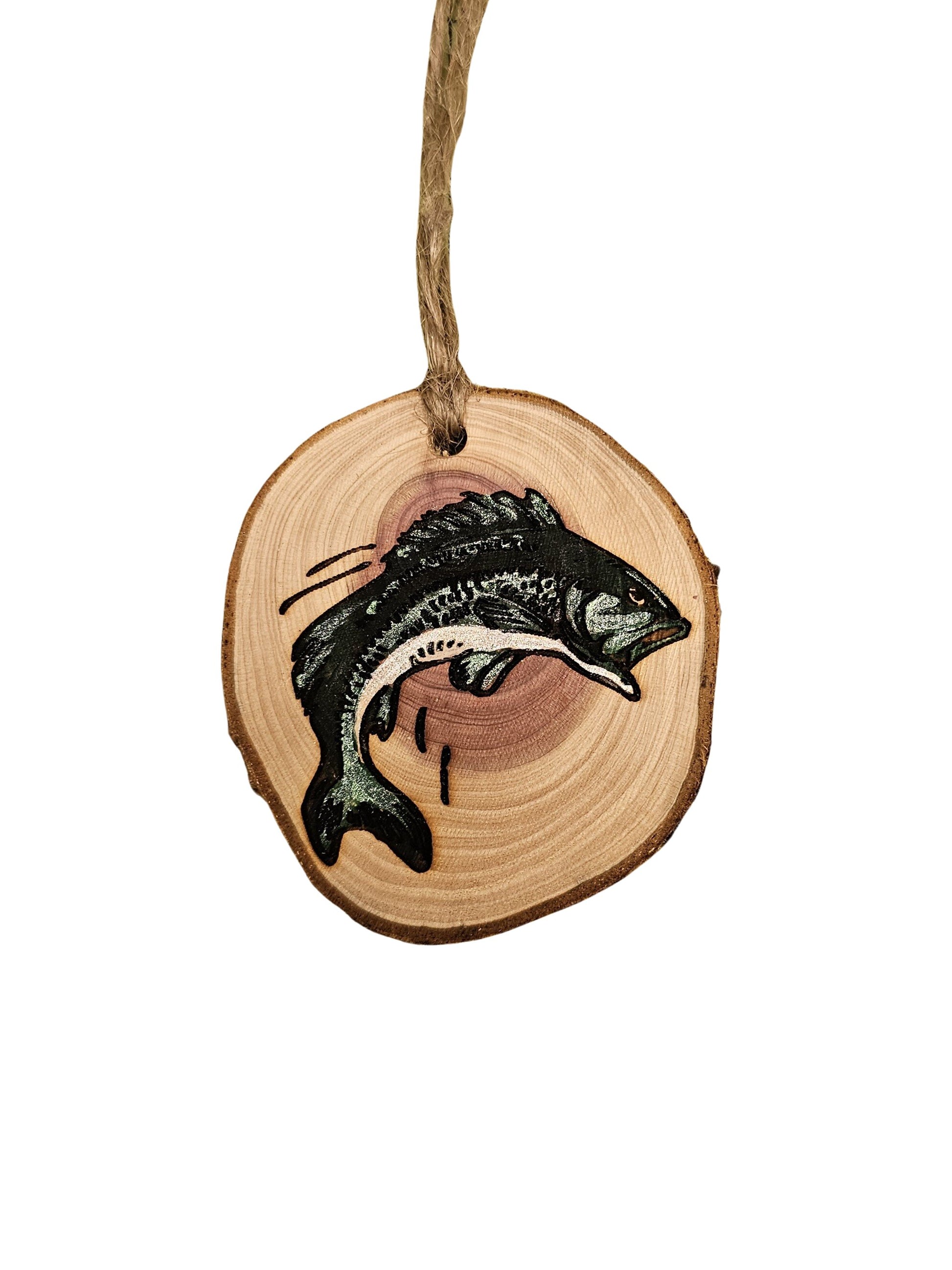 A wood burned Christmas tree ornament depicting a smallmouth bass with a laser engraved hand drawn design, suspended by a twine string.