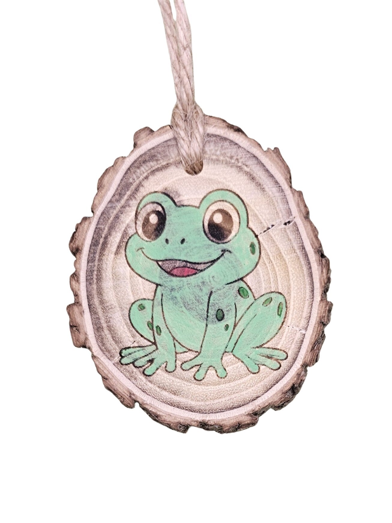 A wood burned Christmas tree ornament depicting a frog with a laser engraved hand drawn design, suspended by a twine string.
