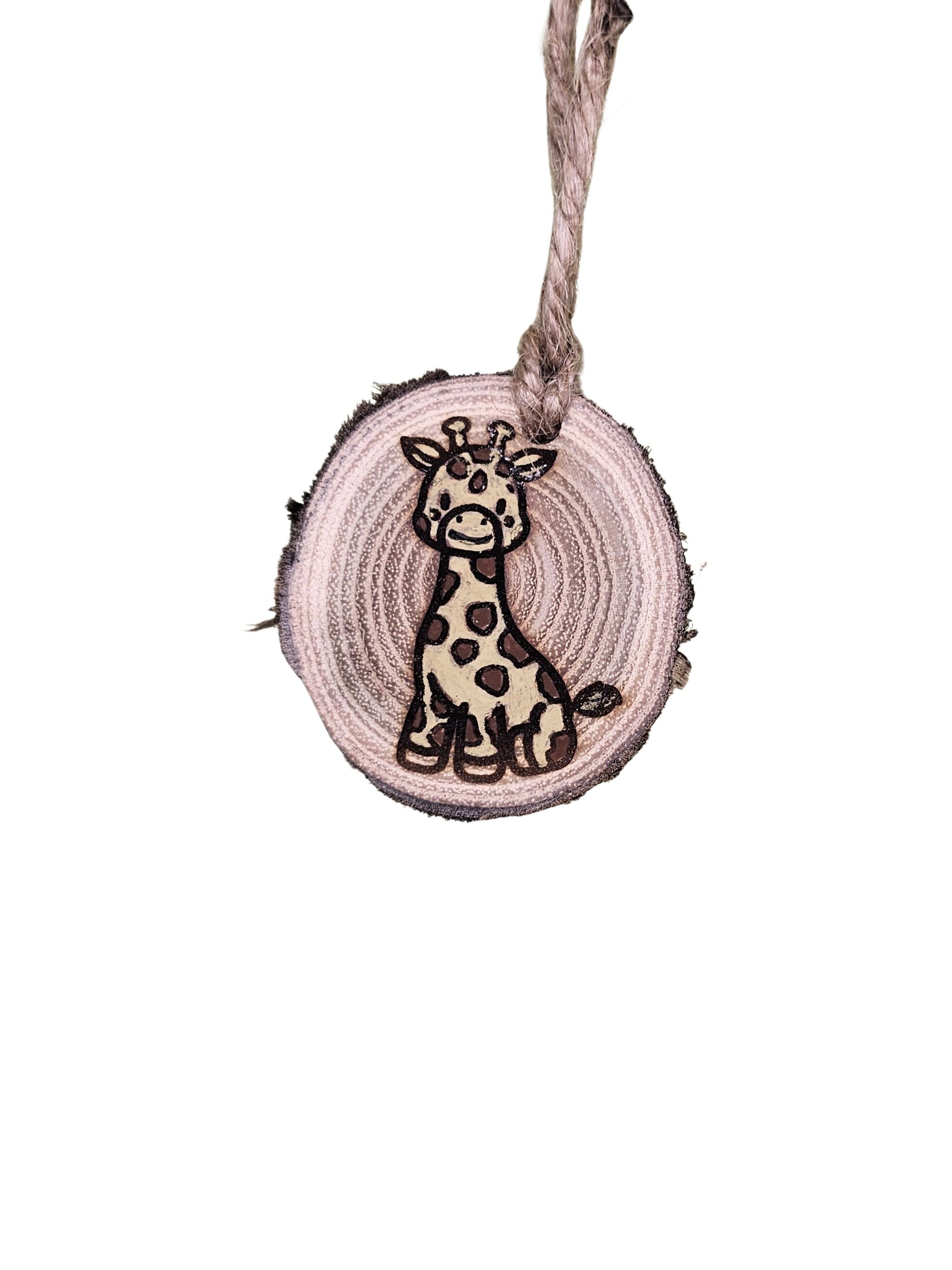A wood burned Christmas tree ornament depicting a giraffe with a laser engraved hand drawn design, suspended by a twine string.